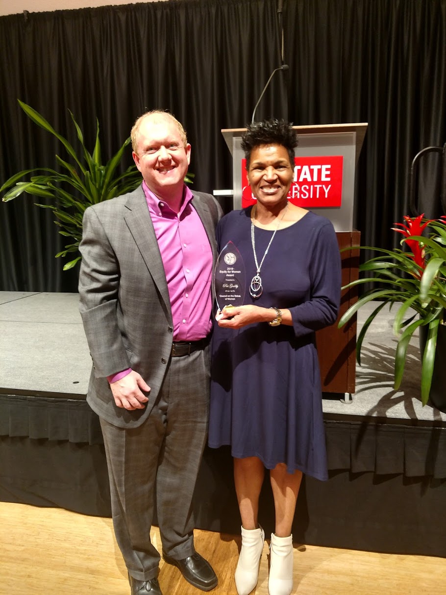 Pat Gaddy holds an award, standing with Greg Sparks.